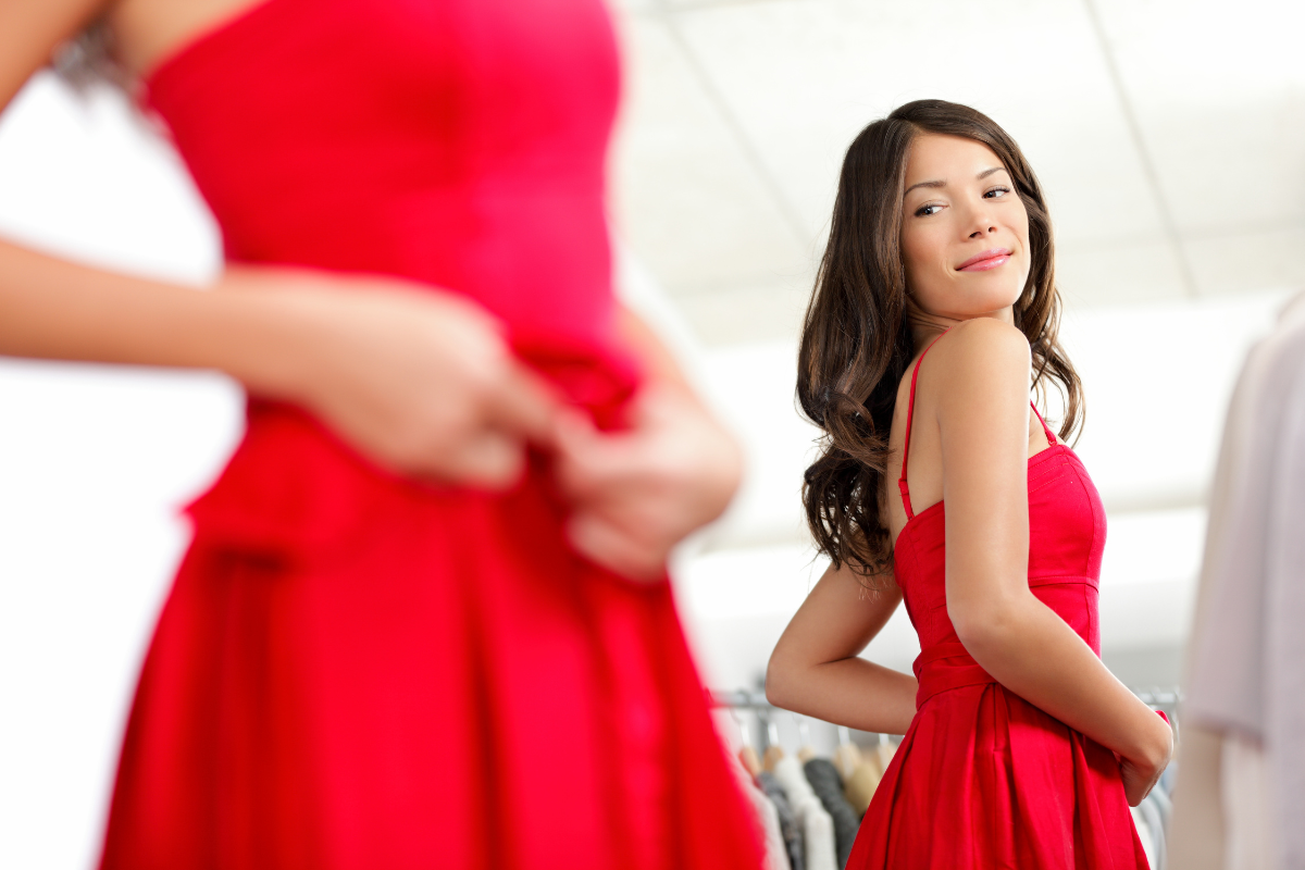 鏡の前で赤いドレスを試着する女性