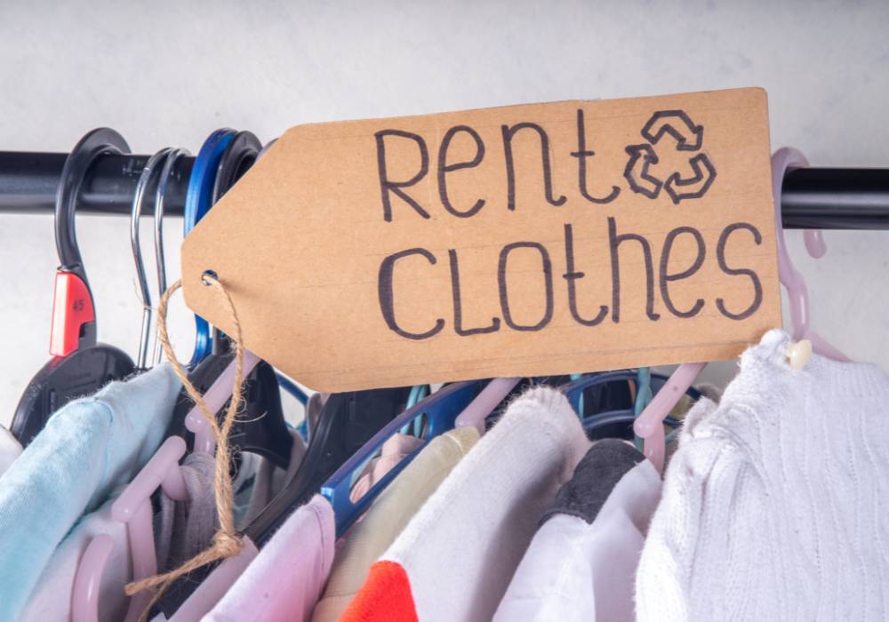 衣類が並ぶハンガーラックと、リサイクルマークとともに「Rent Clothes」と書かれた茶色の値札タグ
