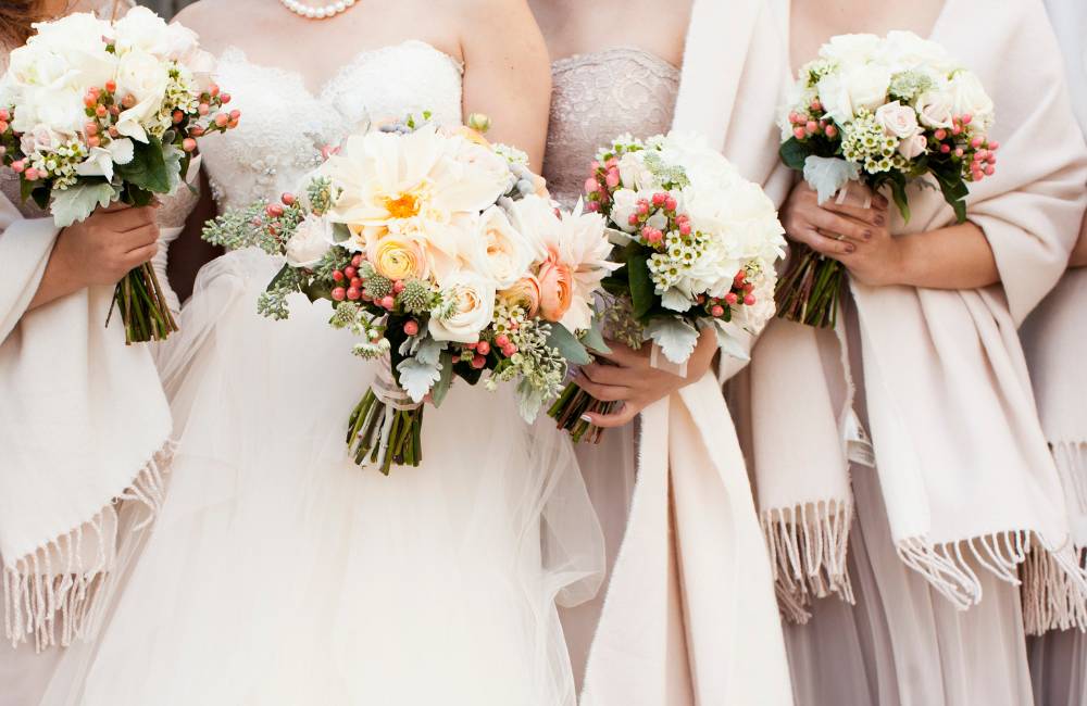 結婚式で華やかなドレス姿の女性たちがブーケを持つお呼ばれシーンのイメージ