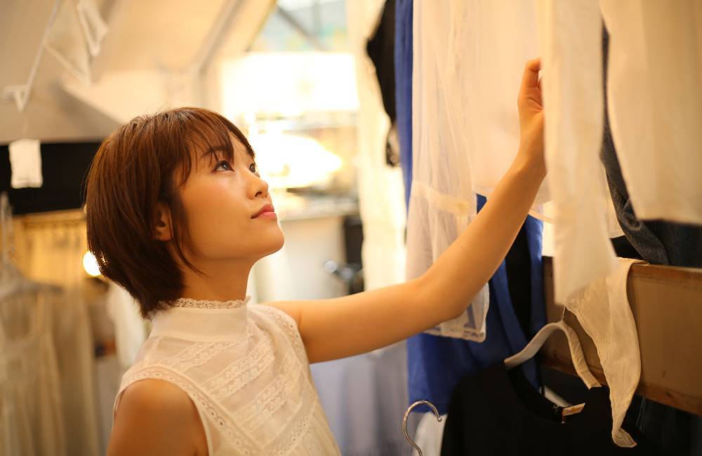 レンタルショップで洋服を確認している女性。店舗でサイズ交換ができるイメージ。