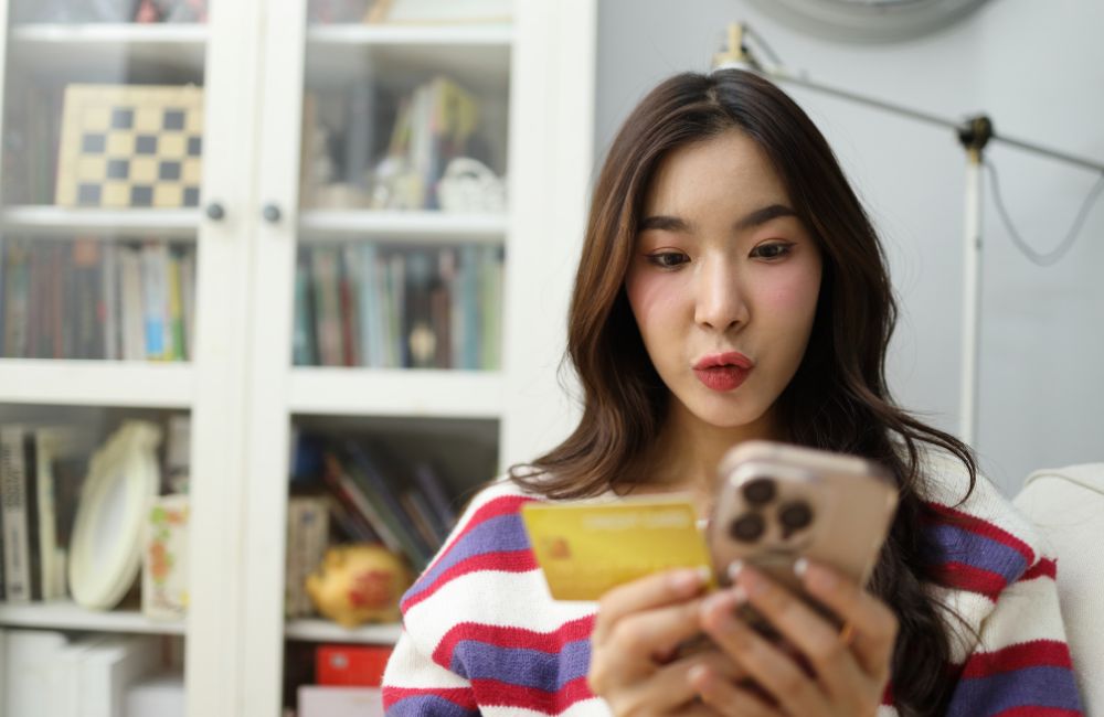 スマートフォンの決済画面を見て追加料金に驚く女性