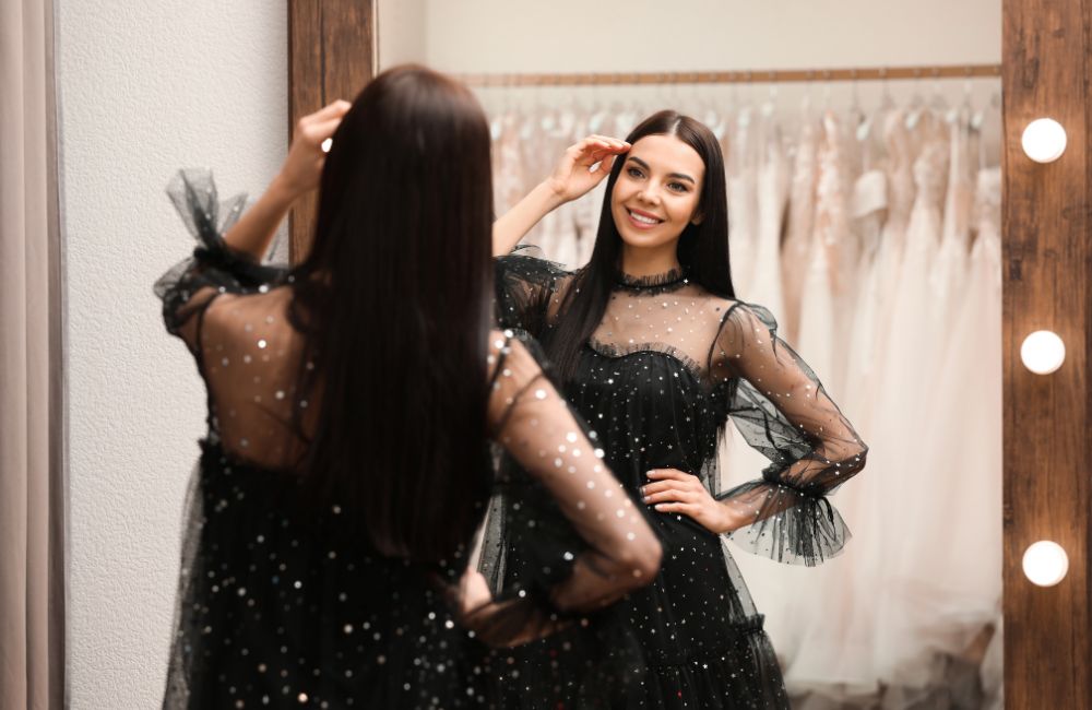 黒いドレスを試着し鏡の前で仕上がりを確認する笑顔の女性