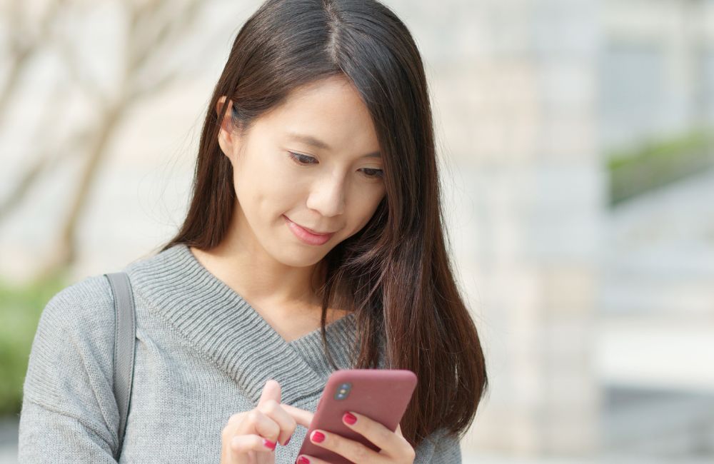 スマートフォンでレンタルドレスを比較しながら選ぶ女