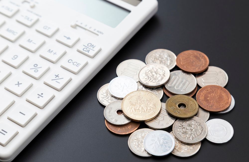 電卓と硬貨を使って送料を含めた費用を計算する様子